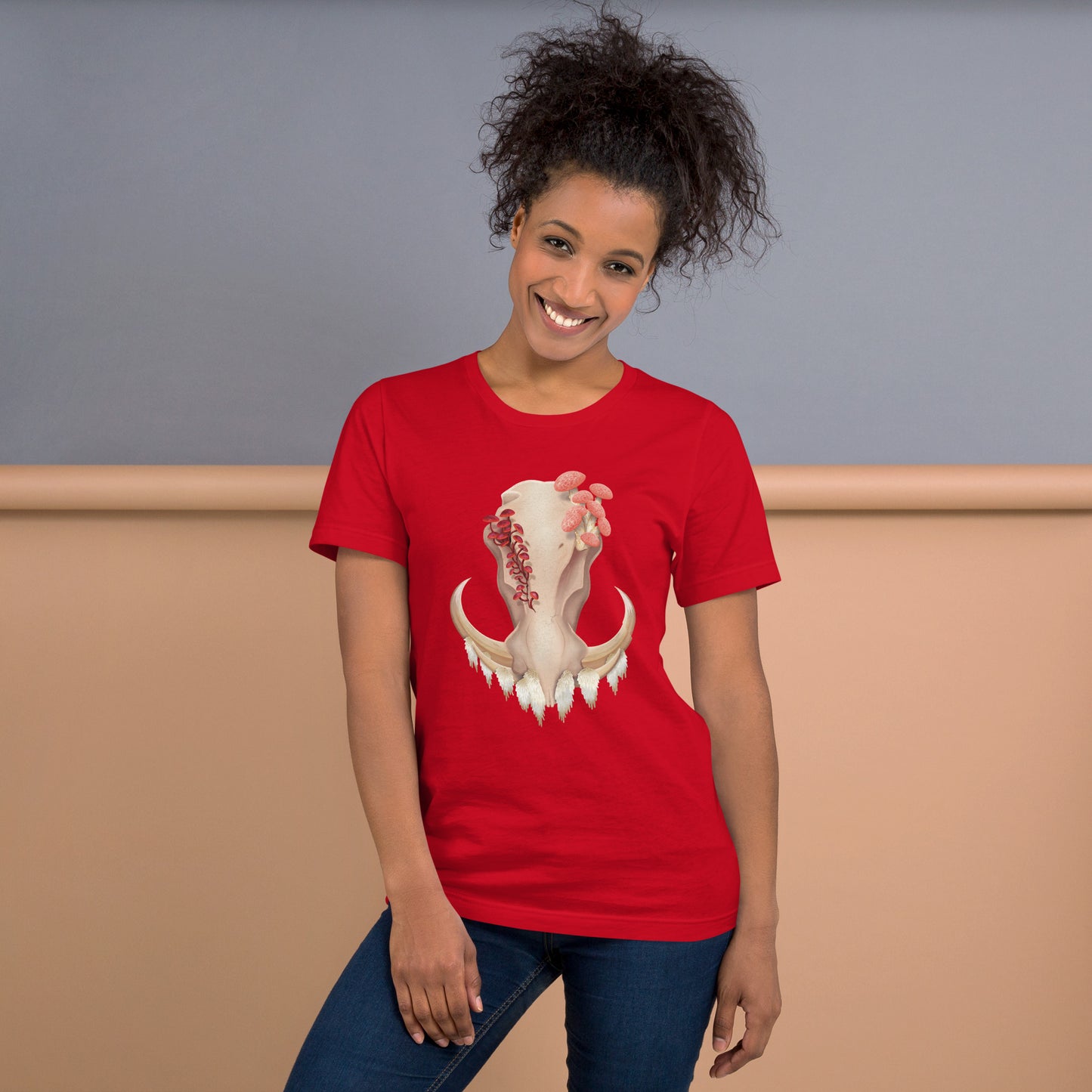 An adult wearing a red colored, unisex T shirt featuring a front facing warthog skull with 3 different kinds of fungi growing out of it